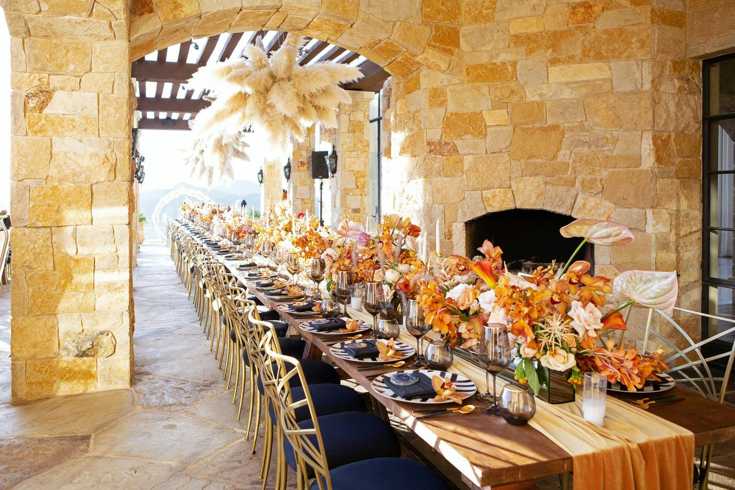 Fall wedding centerpieces of suspended pampas grass and orange flowers | PartySlate