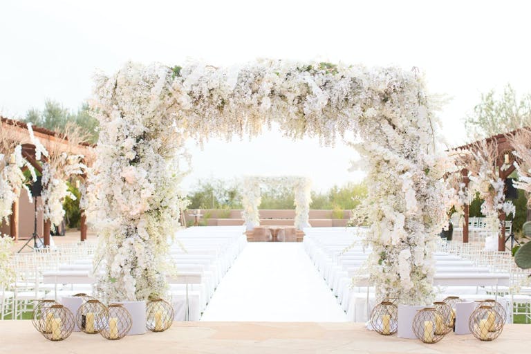 White Floral Arched Alter With White Seating and Pampas Grass | PartySlate