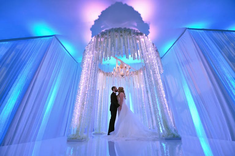 Dramatic White Wedding with Purple and Blue Immerse Experience Lighting and Floral Arch | PartySlate