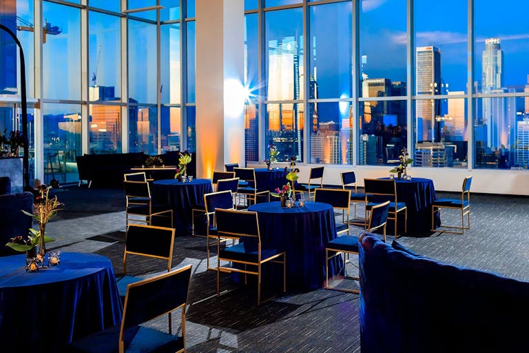 Party with blue lounge seating at Penthouse Suites at South Park Center with dramatic view of Los Angeles, CA | PartySlate