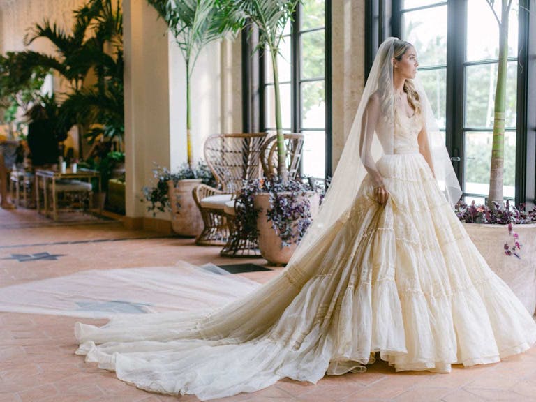 Bride Standing in Timeless Off-White Wedding Dress at Four Seasons Hotel | PartySlate