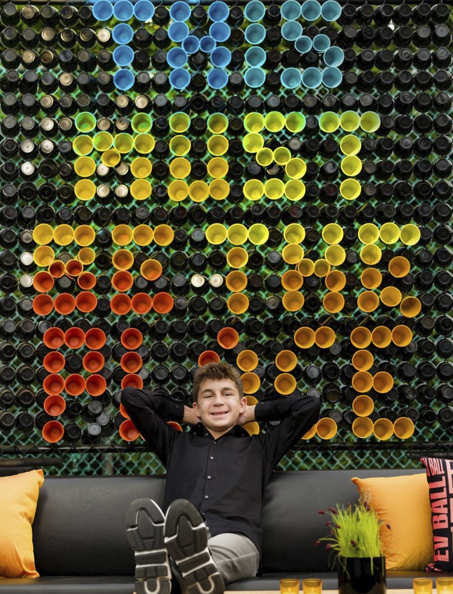 Bar Mitzvah Theme with Birthday Boy on Couch in Front of Personalized Colorful Sinage | PartySlate