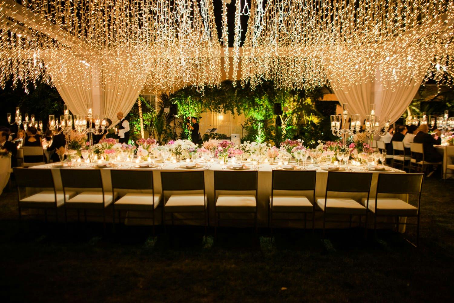 Evening wedding with suspended string lights over tablescap | PartySlate