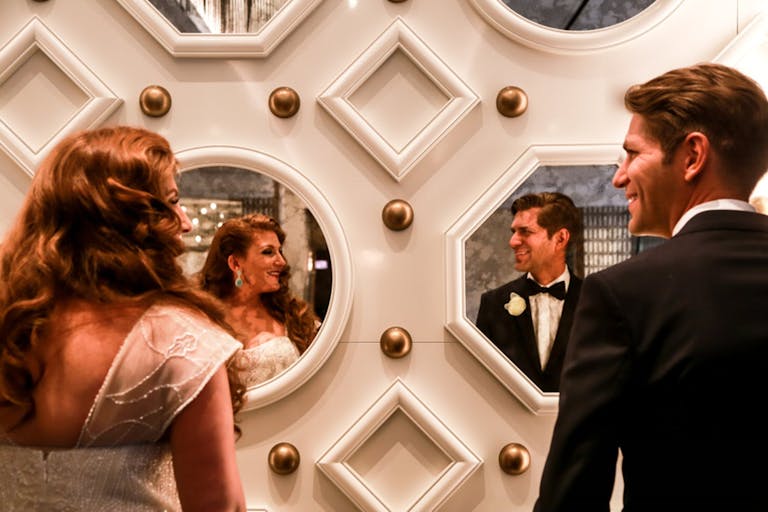 Bride and Groom Standing Together Looking Into Mirrored Wall | PartySlate