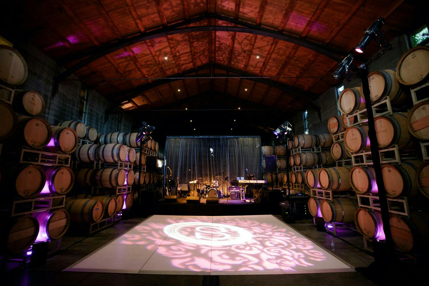 Winery wedding dance floor lined with wine barrels | PartySlate