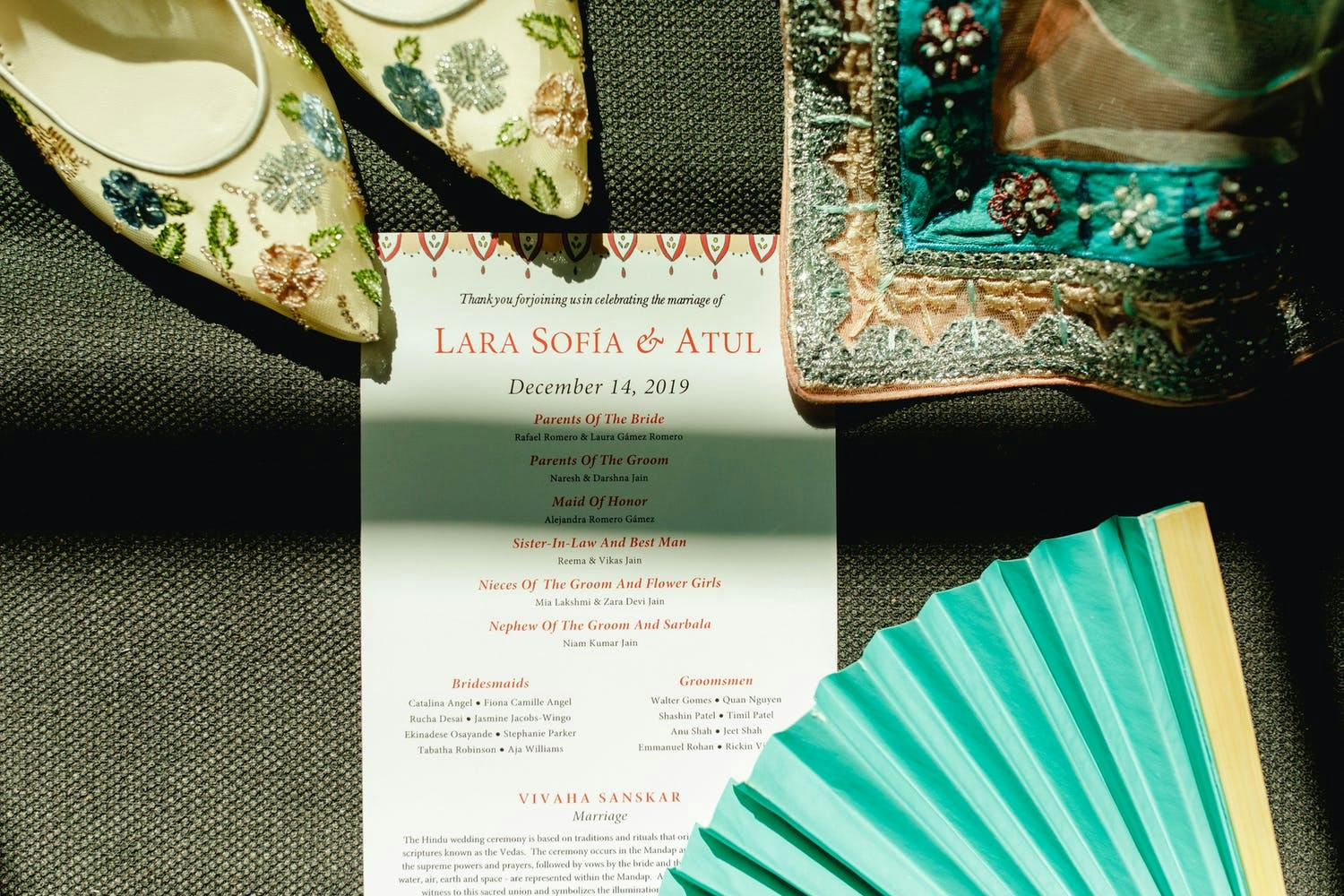 Latin-Indian wedding invitation, teal hand-held fan, and embroidered shoes | PartySlate