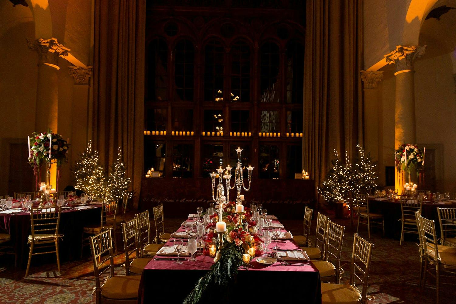 Winter wedding at Biltmore Hotel Miami Coral Gables with amber uplighting and cranberry tablescapes with glass candelabras | PartySlate