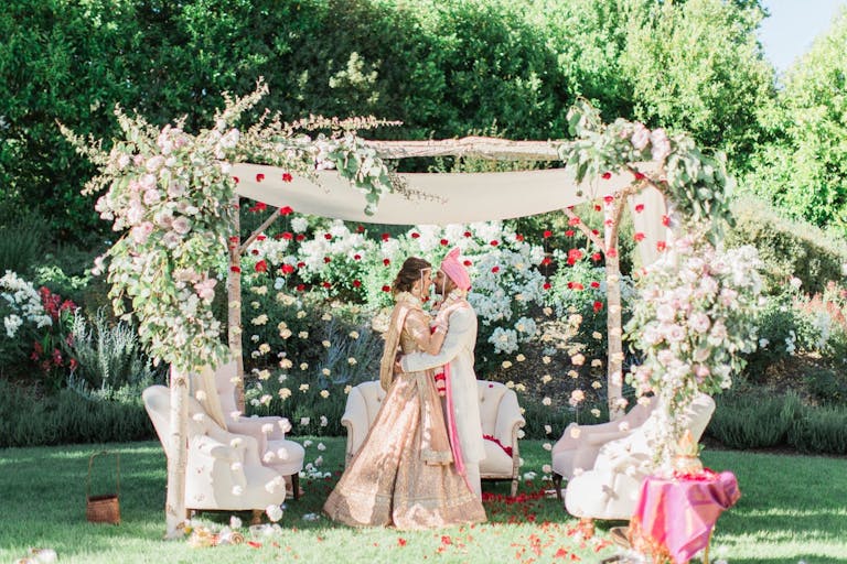 Beautiful Indian and Western Wedding with Greenery and Florals and Cuple Kissing at the Alter | PartySlate
