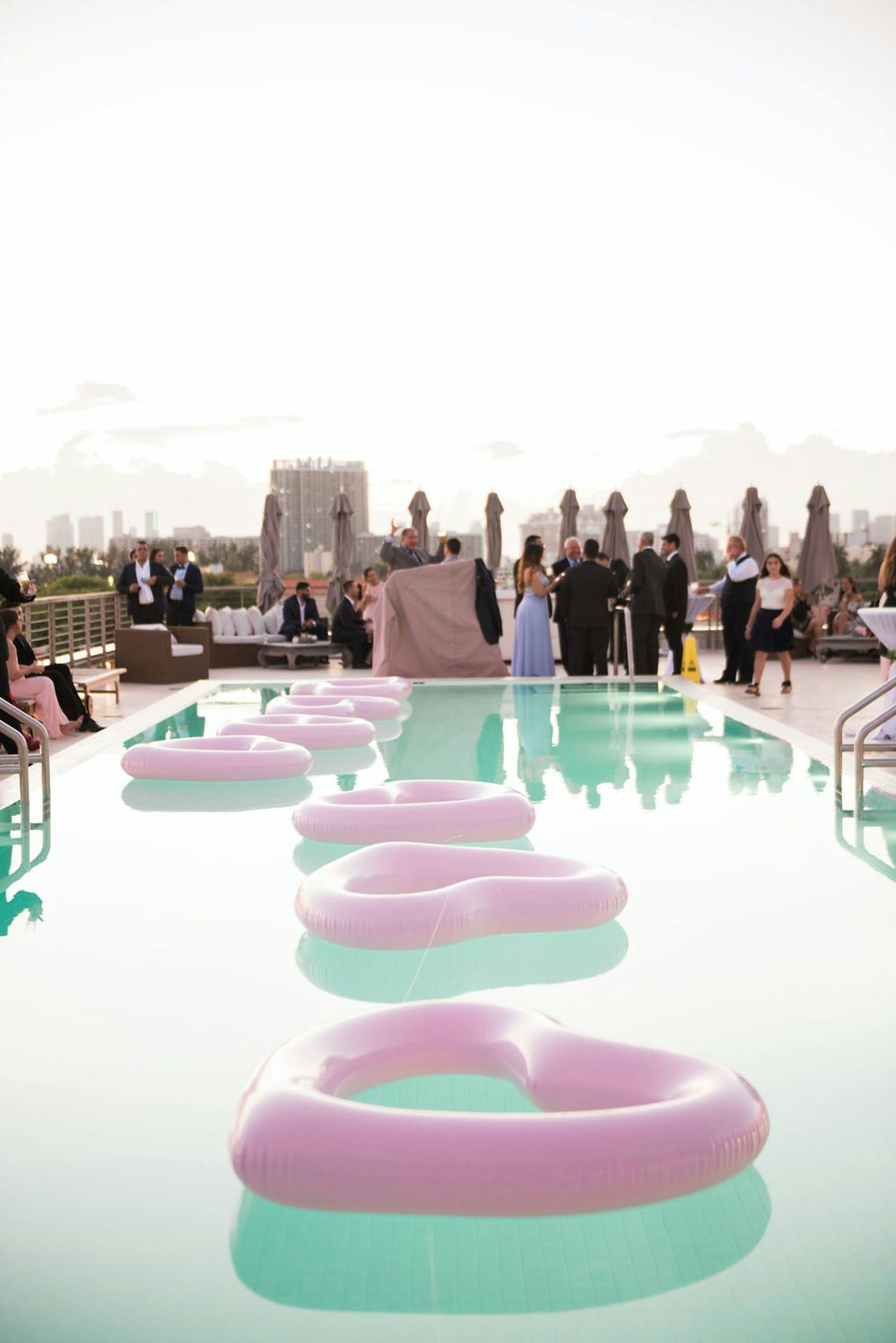 Rooftop wedding with pink heart-shaped pool inflatables | PartySlate