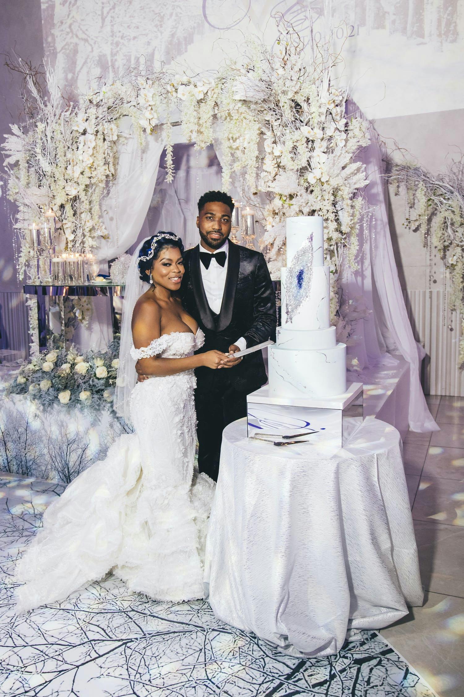 Bride and groom cut into white geode cake at winter wonderland wedding | PartySlate