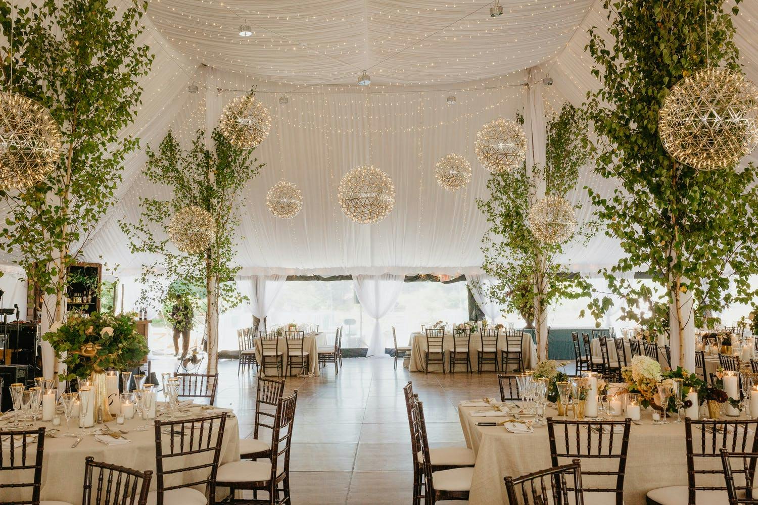 White tented wedding with towering tree décor and geometric chandeliers | PartySlate