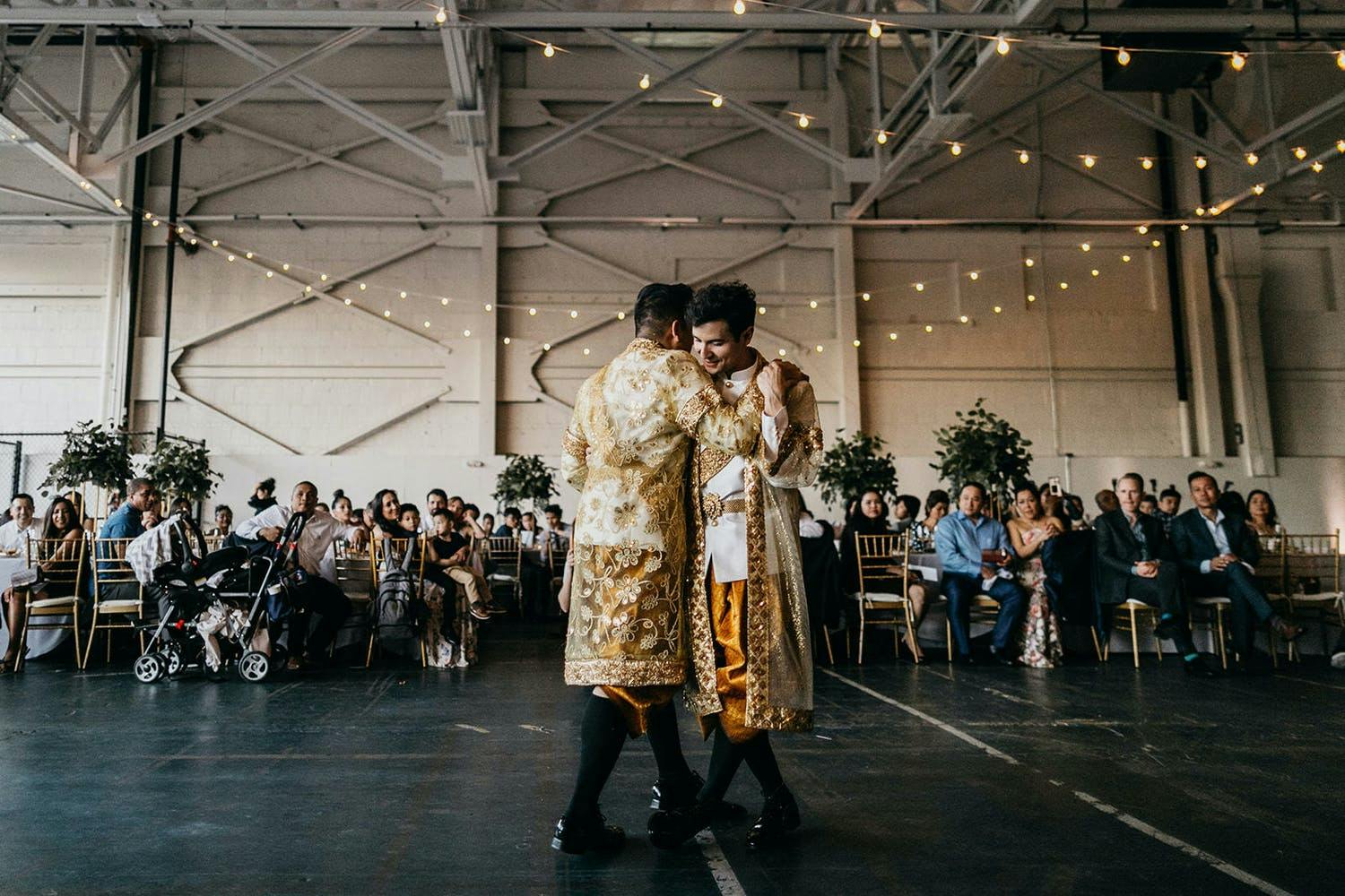 Two grooms dance in Cambodian attire at industrial-chic wedding | PartySlate