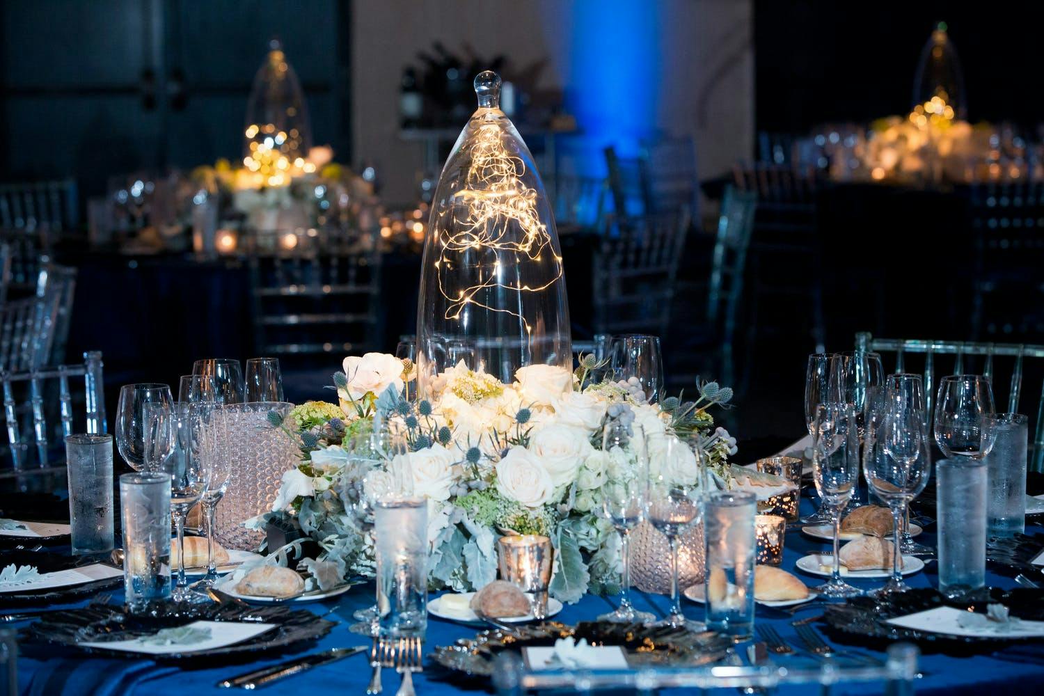 Winter wedding with cloche jar centerpiece filled with twinkling lights and surrounded by pale flowers | PartySlate