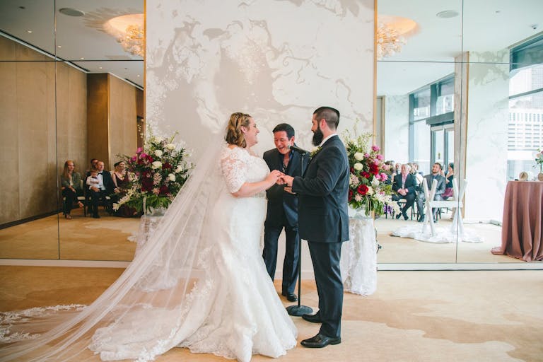 Bride and Groom at Wedding Ceremony with Mirrored Wall Behind | PartySlate
