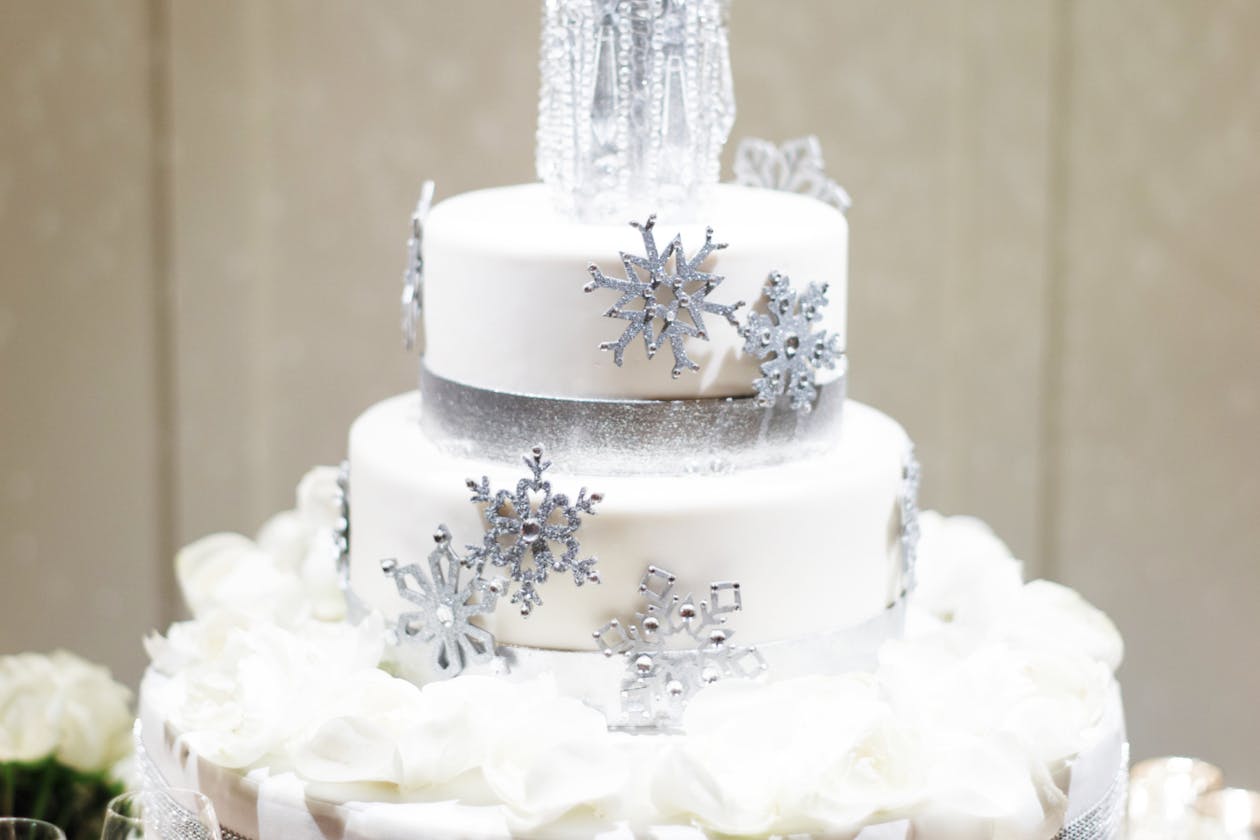White winter wedding cake with silver glittery snowflake designs | PartySlate