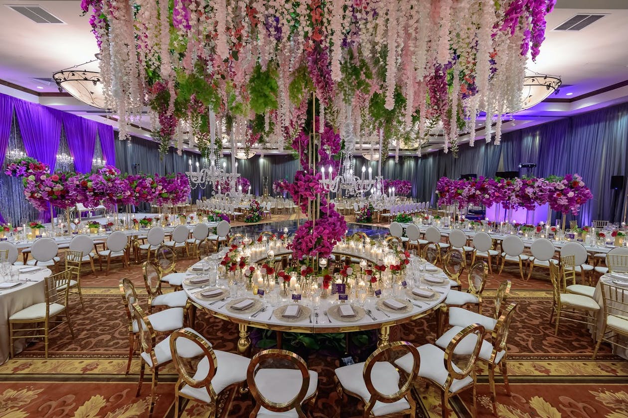 Indian wedding feast with towering pink and purple floral centerpieces | PartySlate