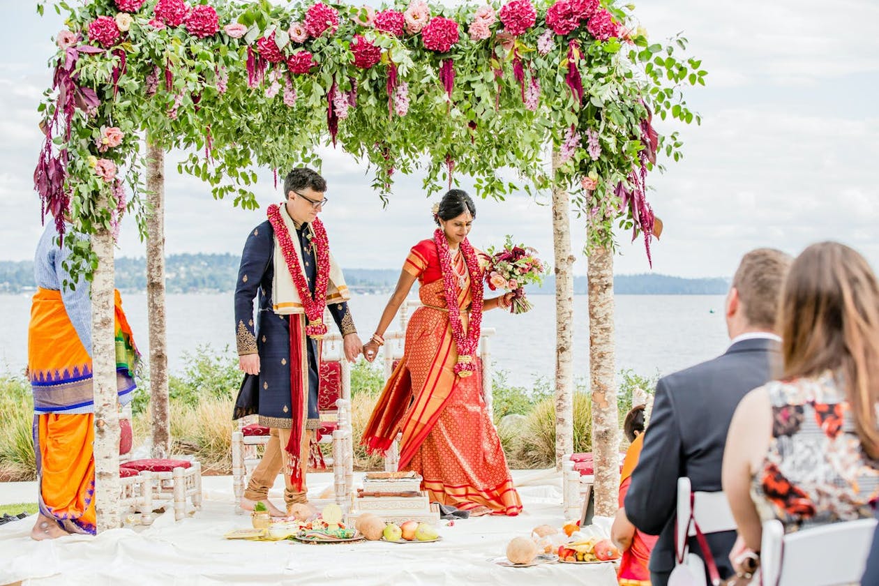Oceanside Indian wedding with beachy mandap crowned in wild greenery and bright pink flowers | PartySlate