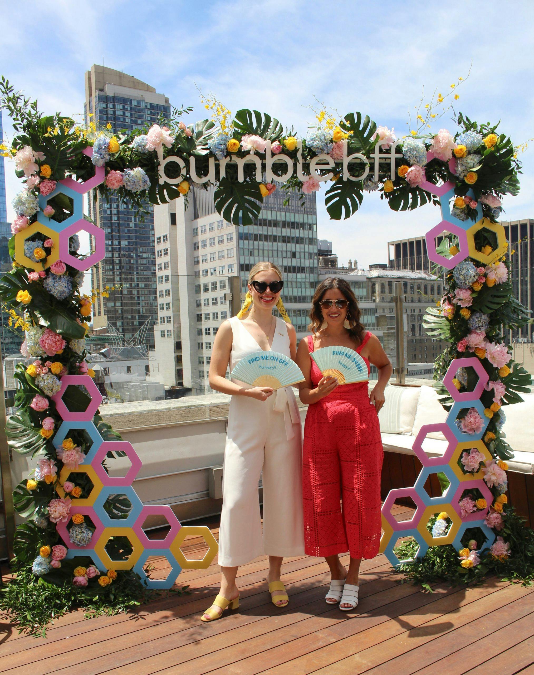 Women pose under tropical archway at Bumble BFF National Best Friends Day Event | PartySlate