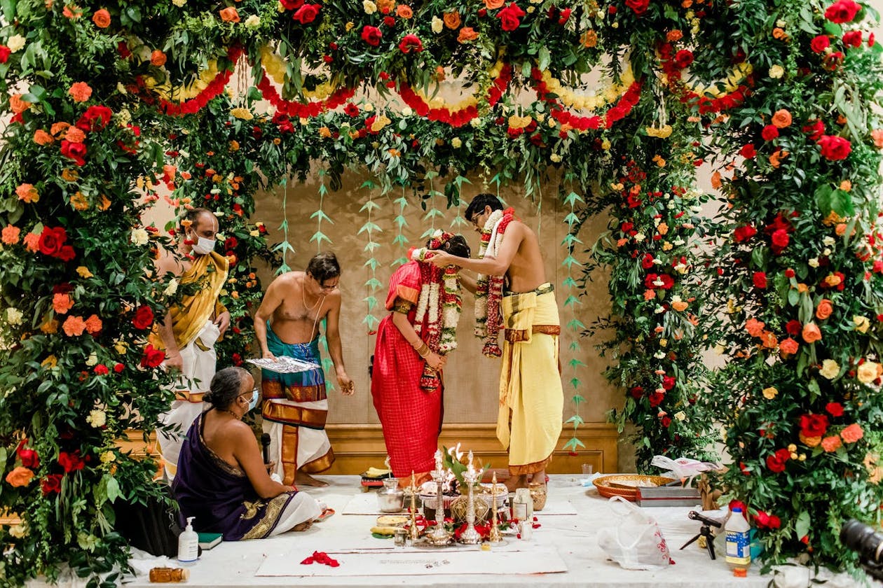 Wedding mandap with lavish greenery and red and yellow flowers | PartySlate