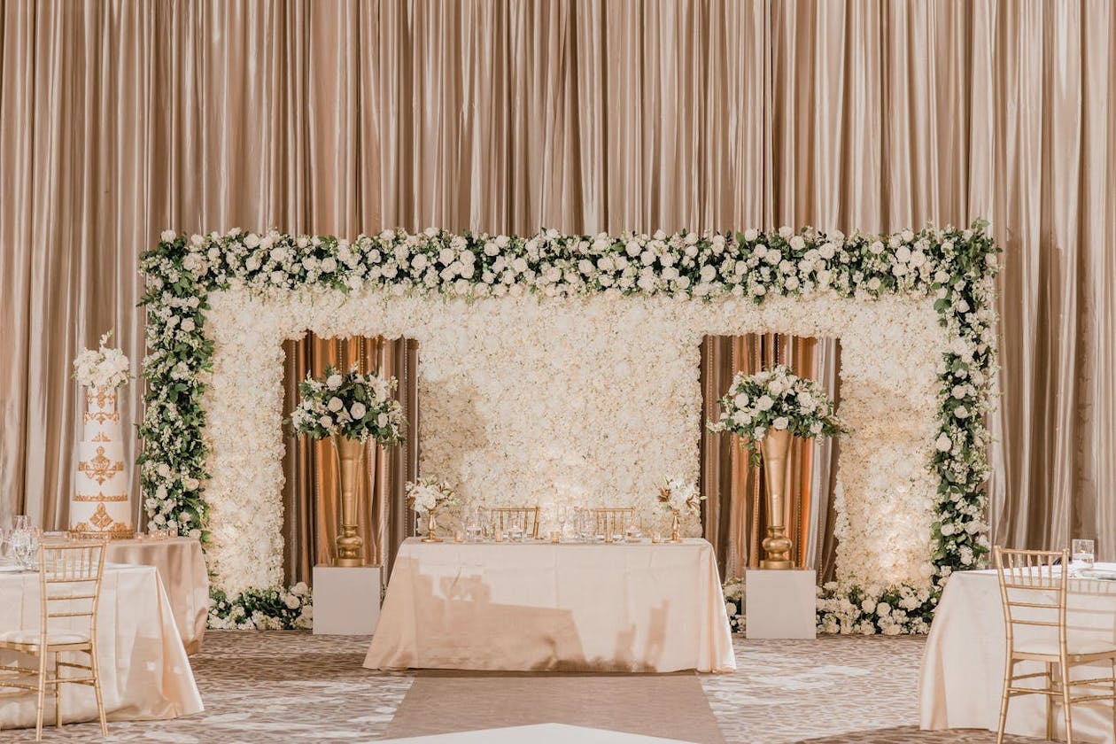 Indian ballroom wedding feast with sweetheart table and backdrop of white blooms | PartySlate