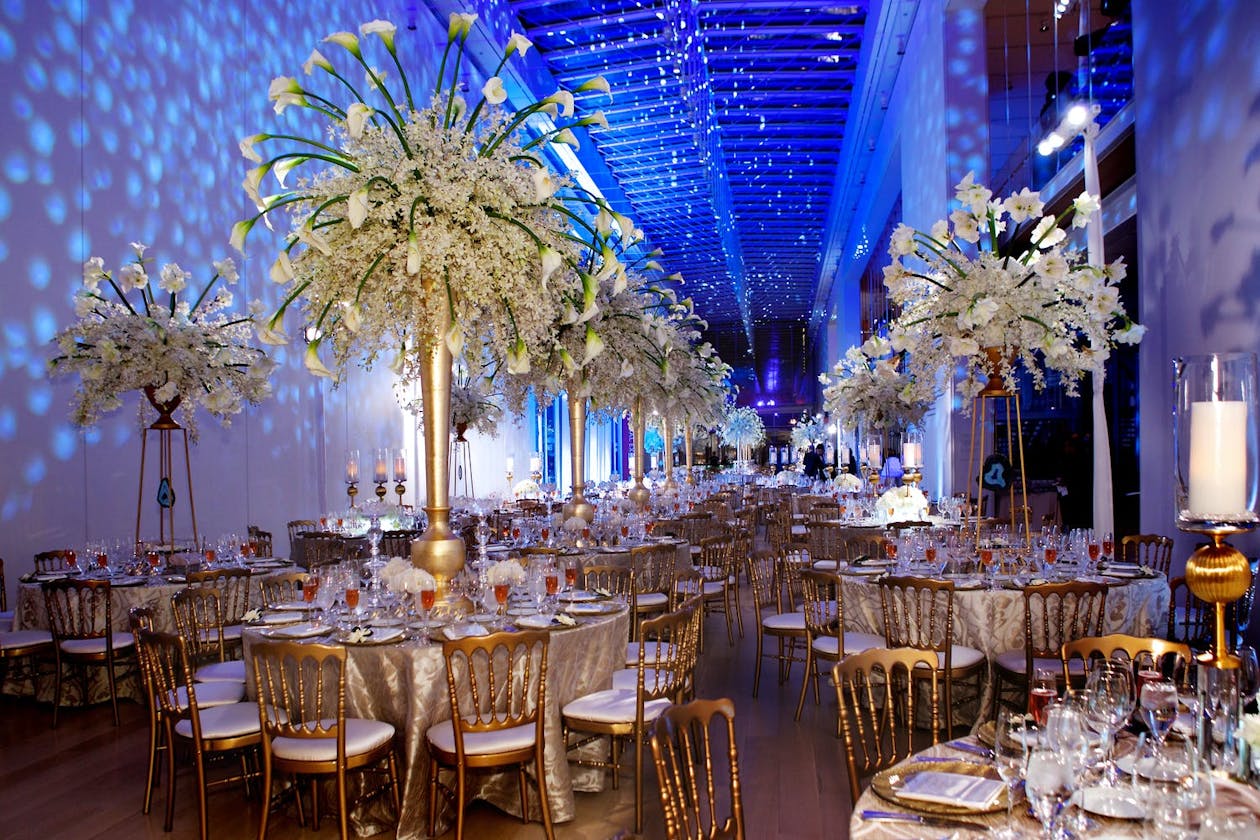 Winter wedding reception with towering white floral centerpieces and blue uplighting | PartySlate
