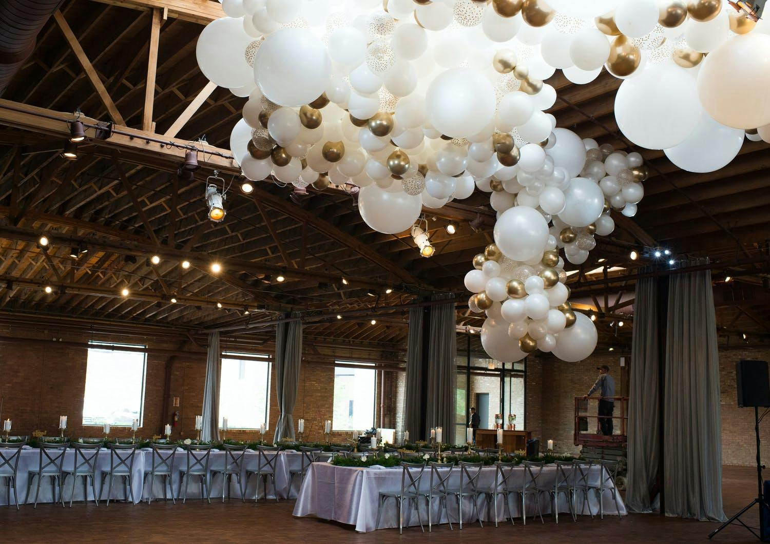 Giant white and gold balloon ceiling installation at rustic-style wedding | PartySlate