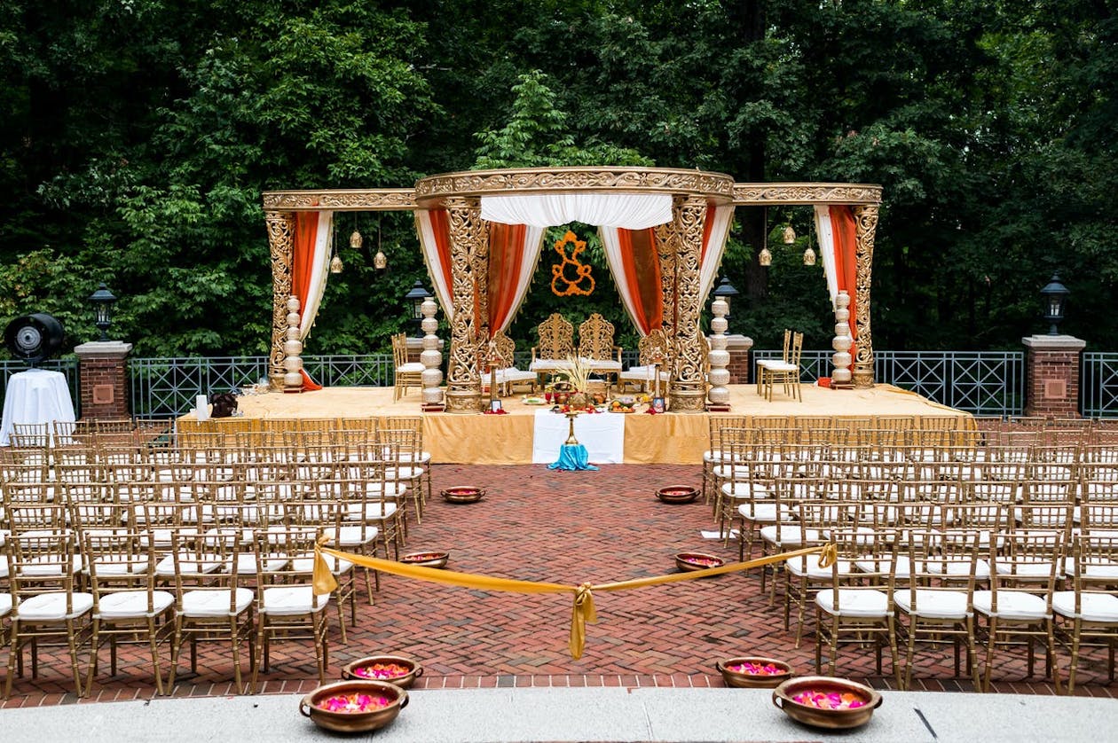 Ornate golden mandap with red drapery for South Indian-Jain Wedding | PartySlate