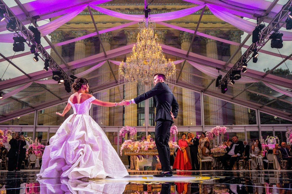First dance at transparent tented wedding with chandelier focal point | PartySlate