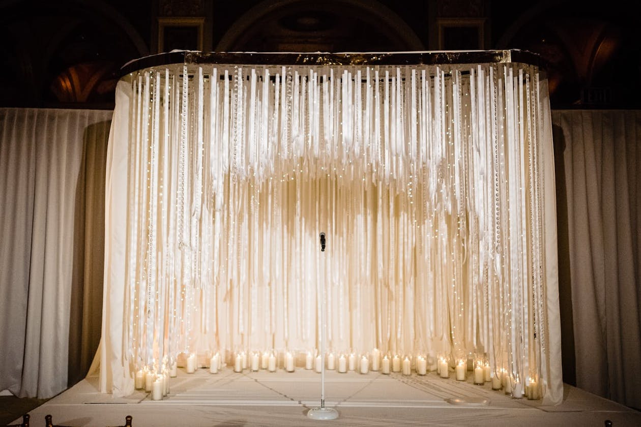 Modern all-white wedding mandap with suspended white floral fringe | PartySlate
