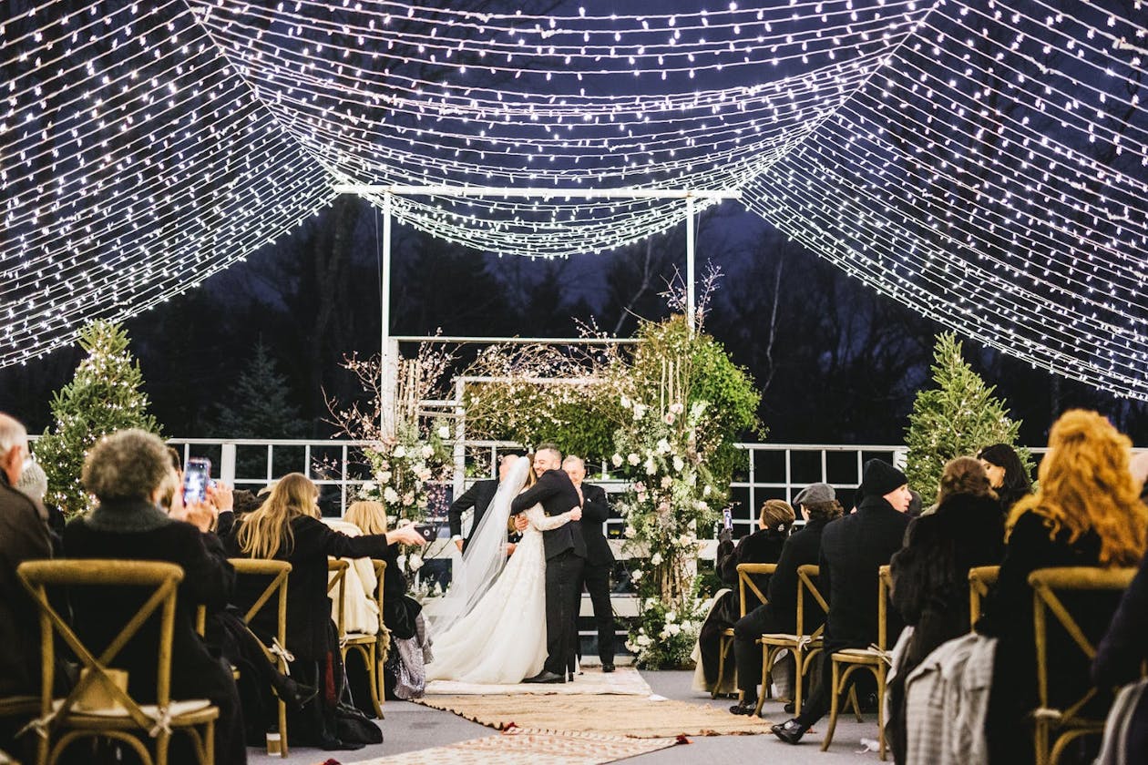 Couple exchanges vows under canopy of string lights | PartySlate