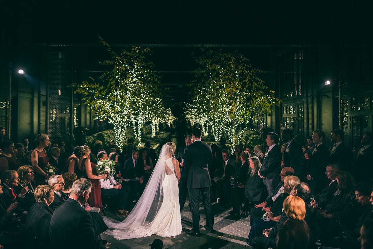 Couple walks down tree-lit aisle at winter wedding ceremony | PartySlate