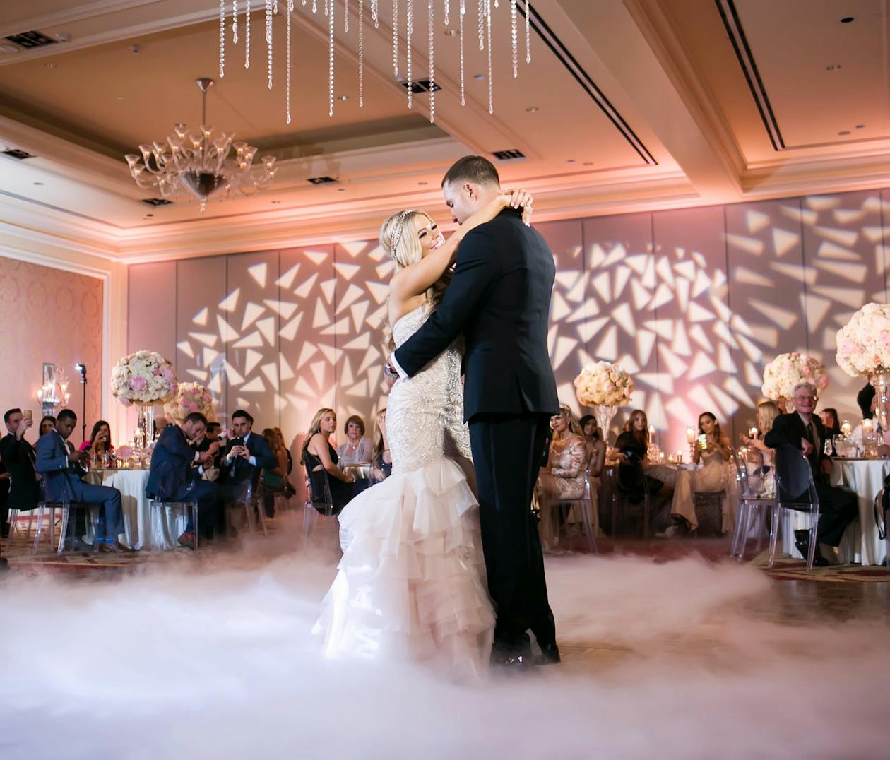 First dance in pink-uplit ballroom with ice fractal lighting projections and swirling fog | PartySlate