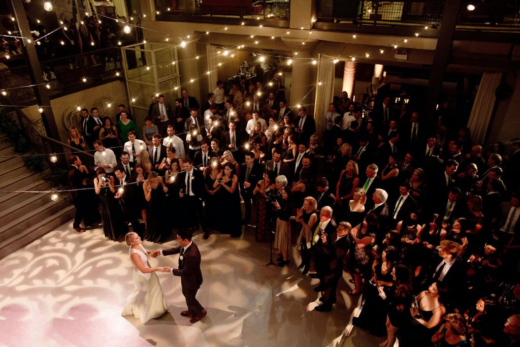 Couples dance at wedding under string lights and on paisley-lit dance floor surrounded by friends and family | PartySlate