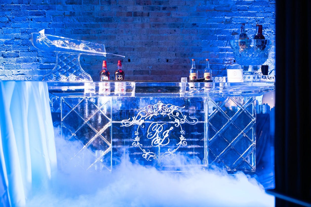 Wedding bar made from ice in room with blue uplighting | PartySlate