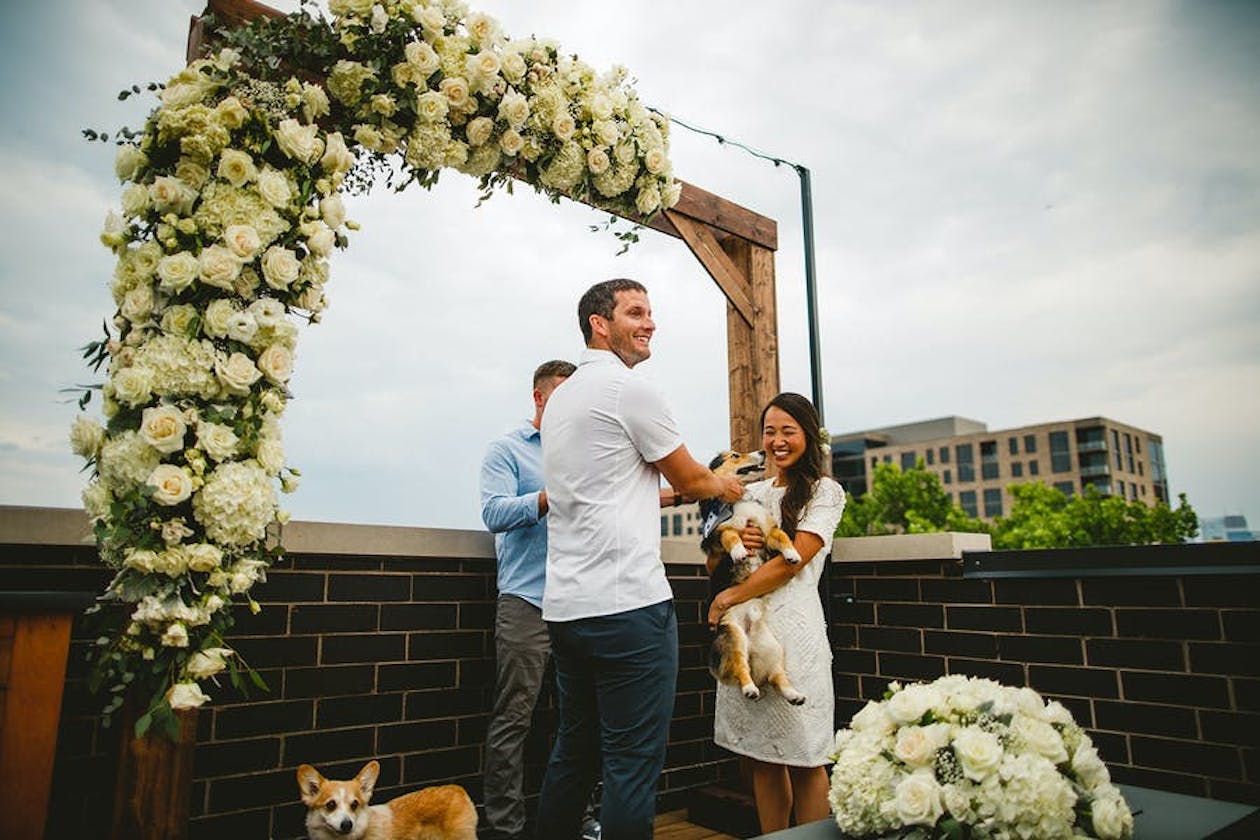 bride holding dog in arms at altar with groom | PartySlate