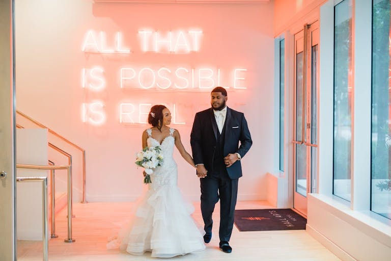 Intimate Celebration at Unique Dallas Wedding Venue with Neon Siiign Behind Couple | PartySlate