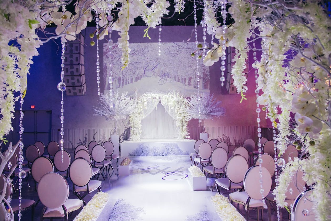 Winter wonderland wedding ceremony with purple uplighting and frosted décor | PartySlate