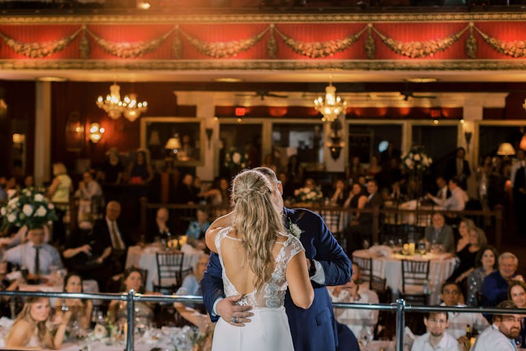 Bride and Groom At The Majestic Metro Wedding With Guests Behind Them | PartySlate