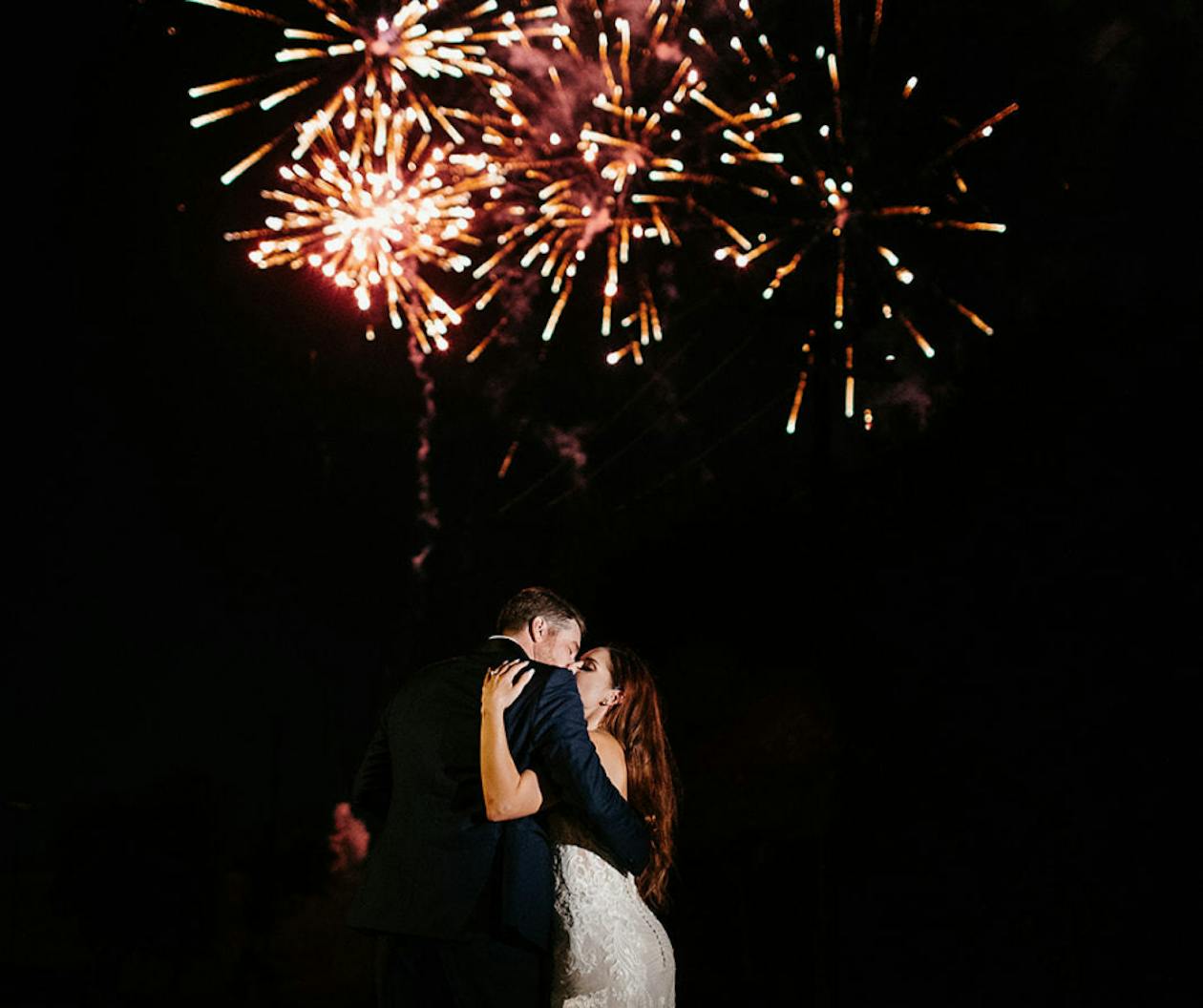 Couple Kissing Under Fireworks at Night Wedding Exit Ideas | PartySlate