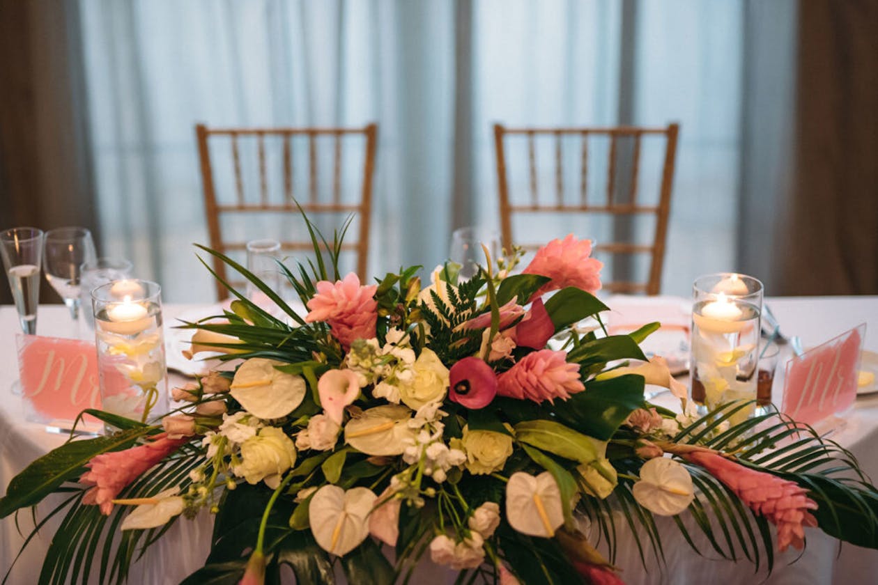 Sweetheart table with tropical pink wedding flowers | PartySlate