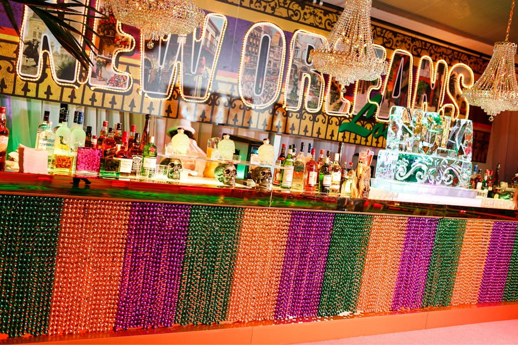 Purple, gold, and green beaded bar area for Mardi Gras Party Theme | PartySlate
