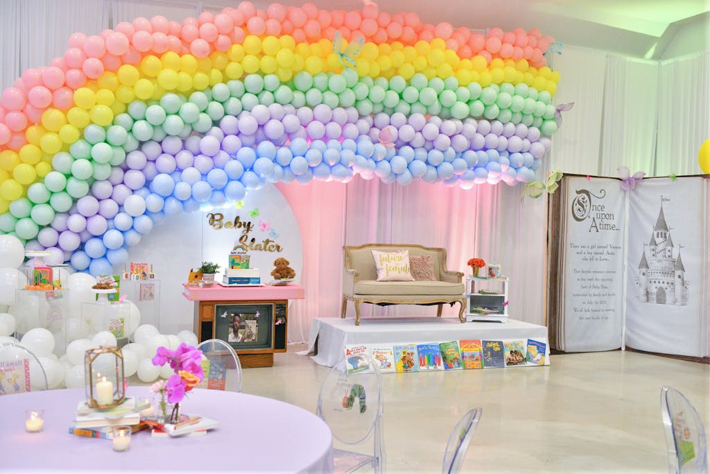 Storybook baby shower with pastel rainbow balloon arch | PartySlate