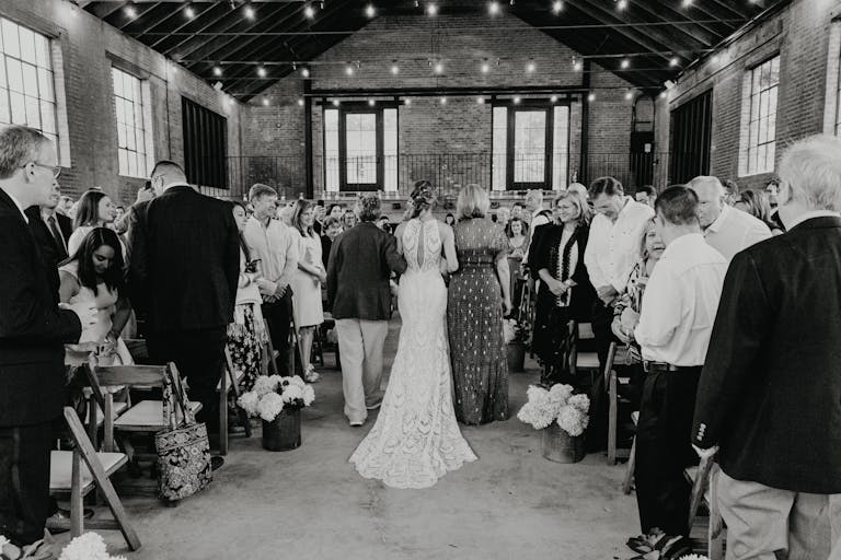 Black and White Photo of Bride Walking Down Aisle At Outdoor Wedding Venue | PartySlate