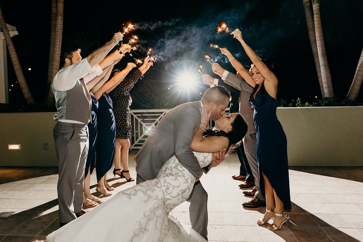 Charming Tropical Wedding at Wyndham Grand Jupiter At Harbourside Place in Jupiter, Florida With Sparklers Wedding Exit and Couple Kissing | PartySlate