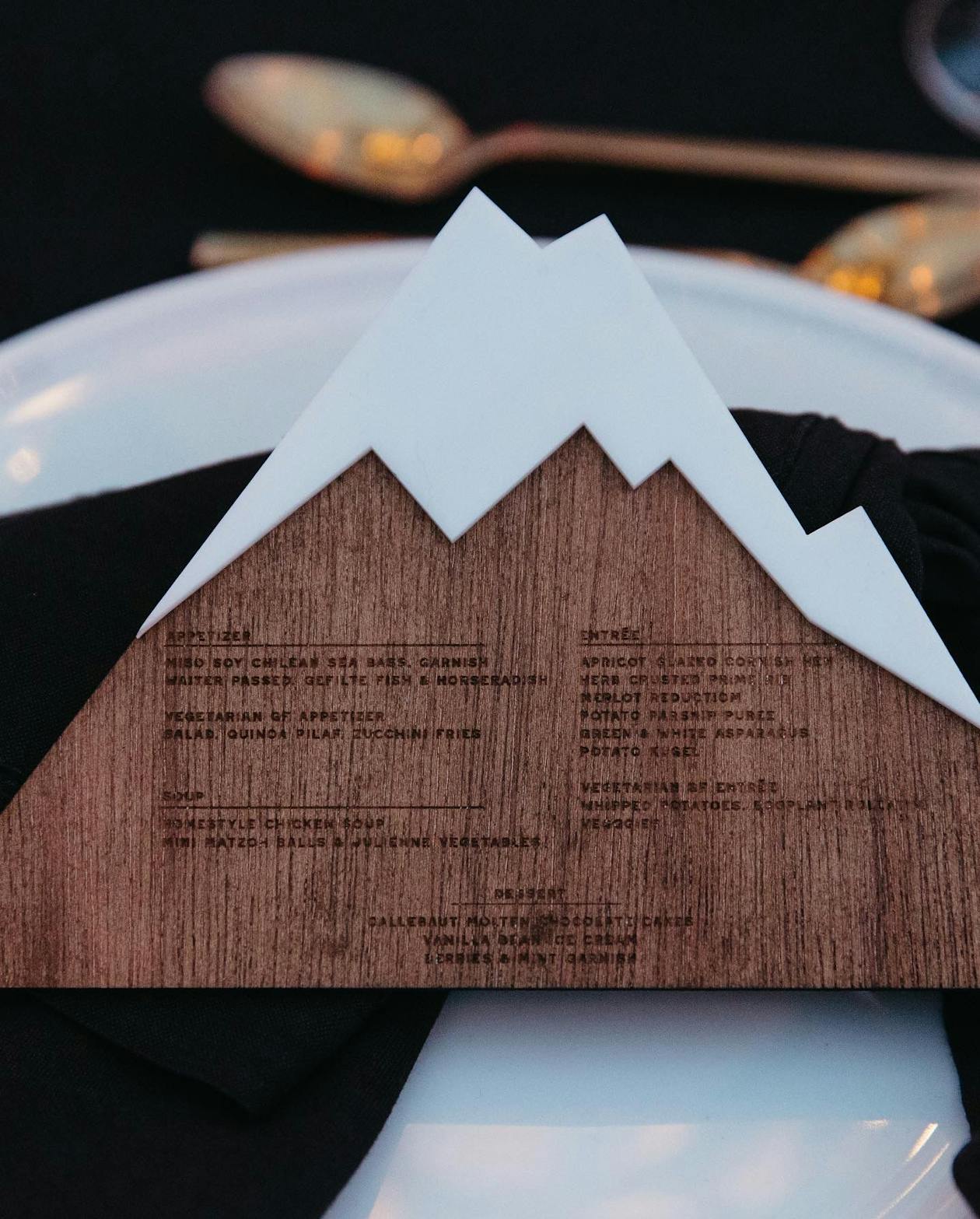 A menu shaped as a mountain on a black tablescape | PartySlate