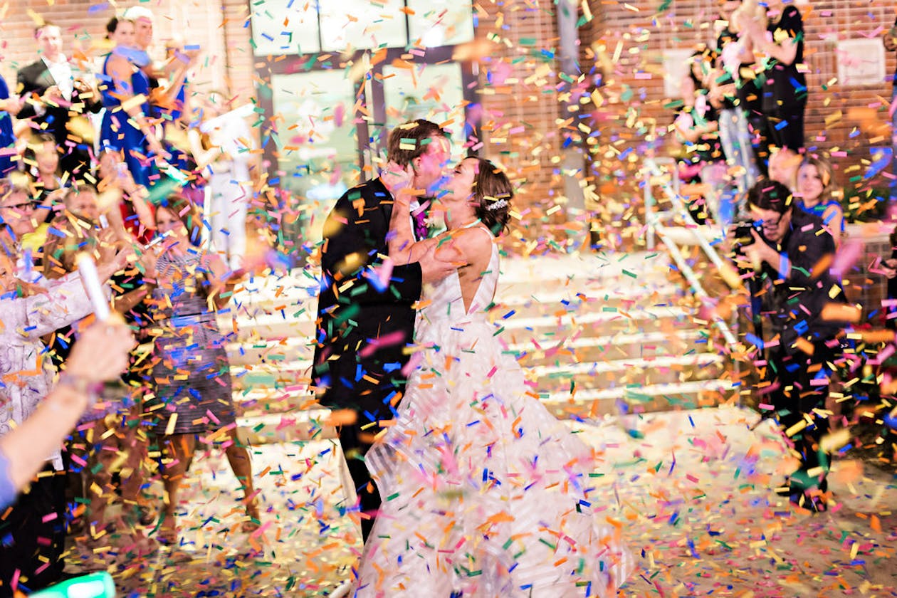 Beautiful Tasteful Wedding Exit Ideas With Colorful Confetti Surrounding Couple | PartySlate