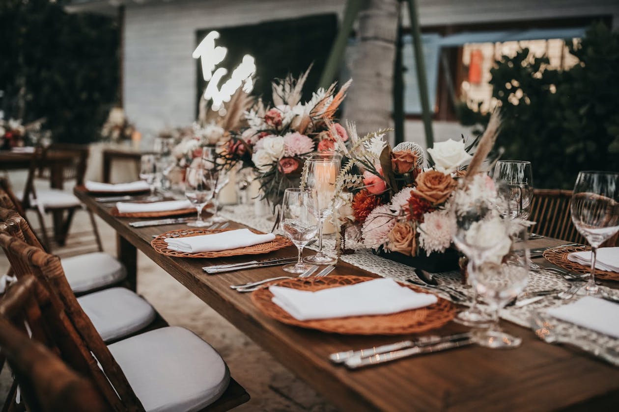 Rustic wooden wedding reception table with boho tropical flowers | PartySlate