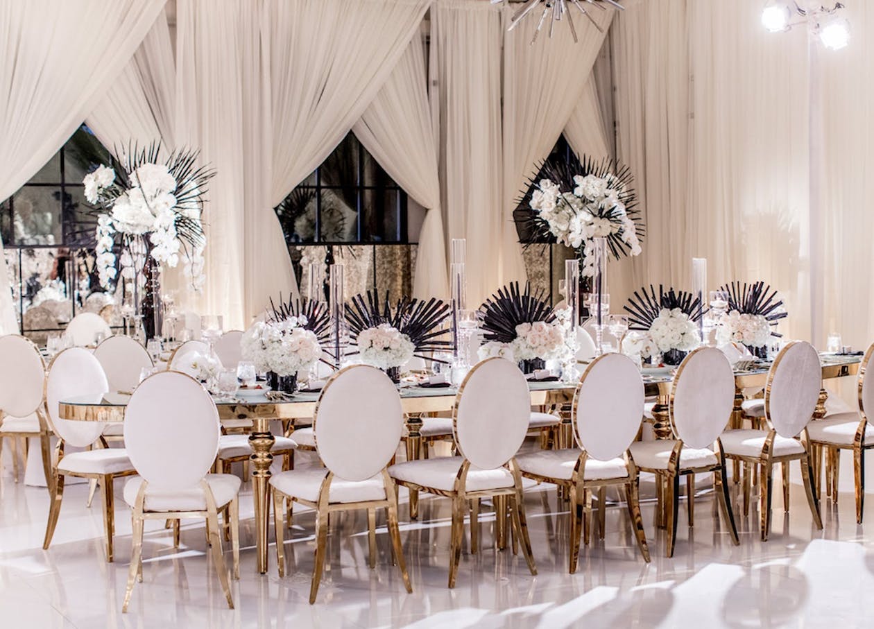 White modern wedding with tropical centerpieces of orchids and black fanned palm leaves | PartySlate