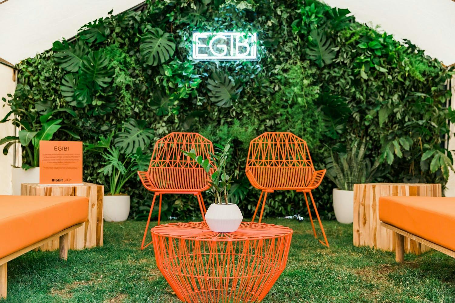 Neon orange lounge seating with foliage backdrop at Ribbit SiFi conference | PartySlate