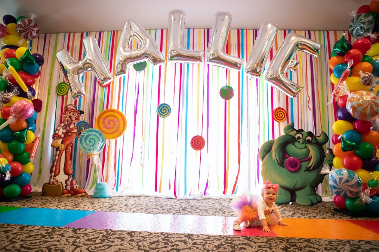 Candy Land Party theme backdrop with Jolly and rainbow track | PartySlate